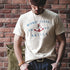 Man wearing a t-shirt with a graphic design in front of a brick wall